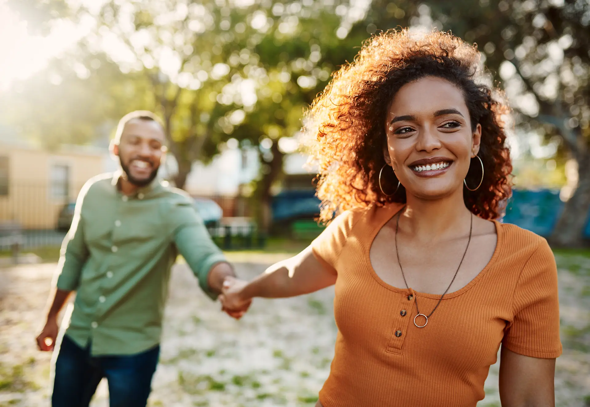 couple holding hands and walking through the park.