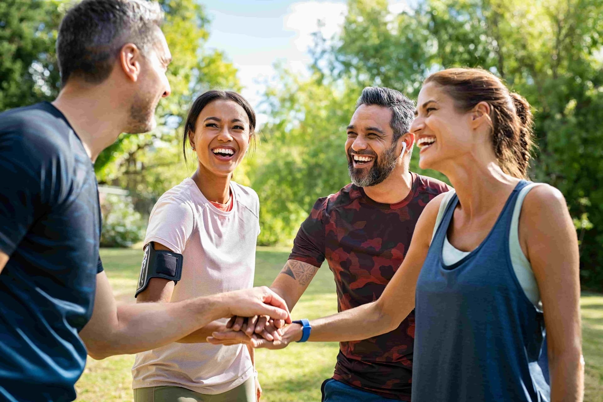 group of friends in athletic attire huddling up in the park