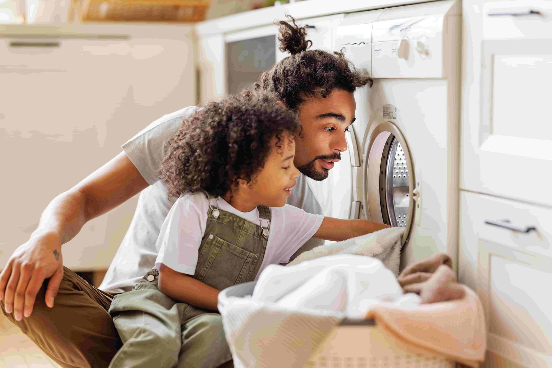 father with his child pulling clothes from the drier.